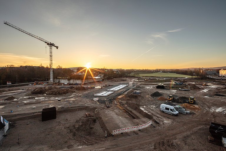 Neubaugebiet in Entwicklung im Projekt joseph – attraktive Immobilienlage Großbaustelle bei Sonnenuntergang mit Kran und Baustellenfahrzeugen